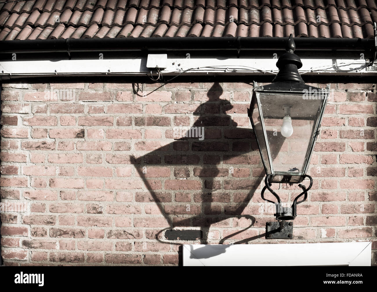 Vintage Lampe montiert an der Wand mit einem Schatten von Sonnenlicht Stockfoto