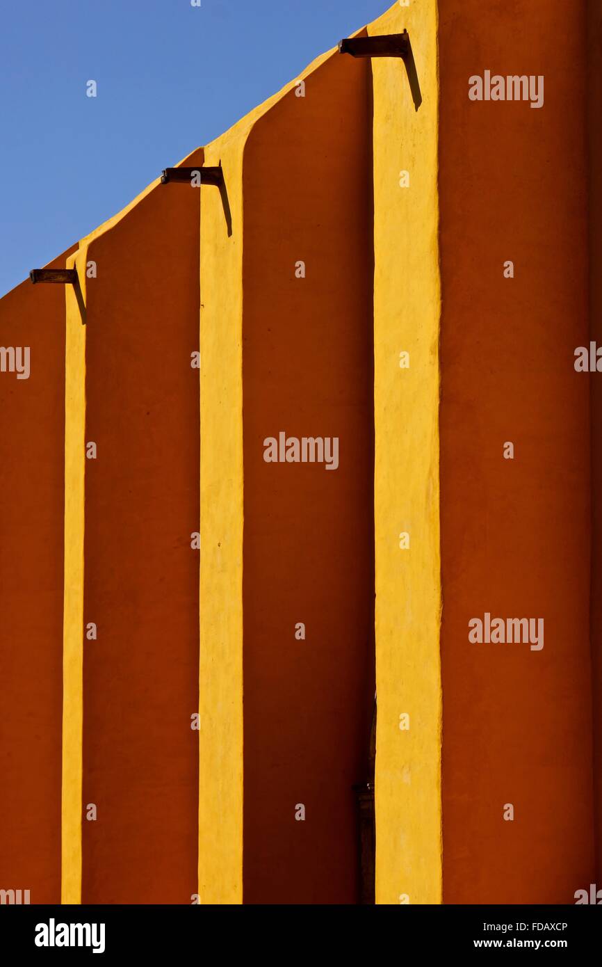 Die leuchtenden gelben Wänden einer Kirche in Mexiko mit der Gosse Tüllen Schattenwurf. Stockfoto