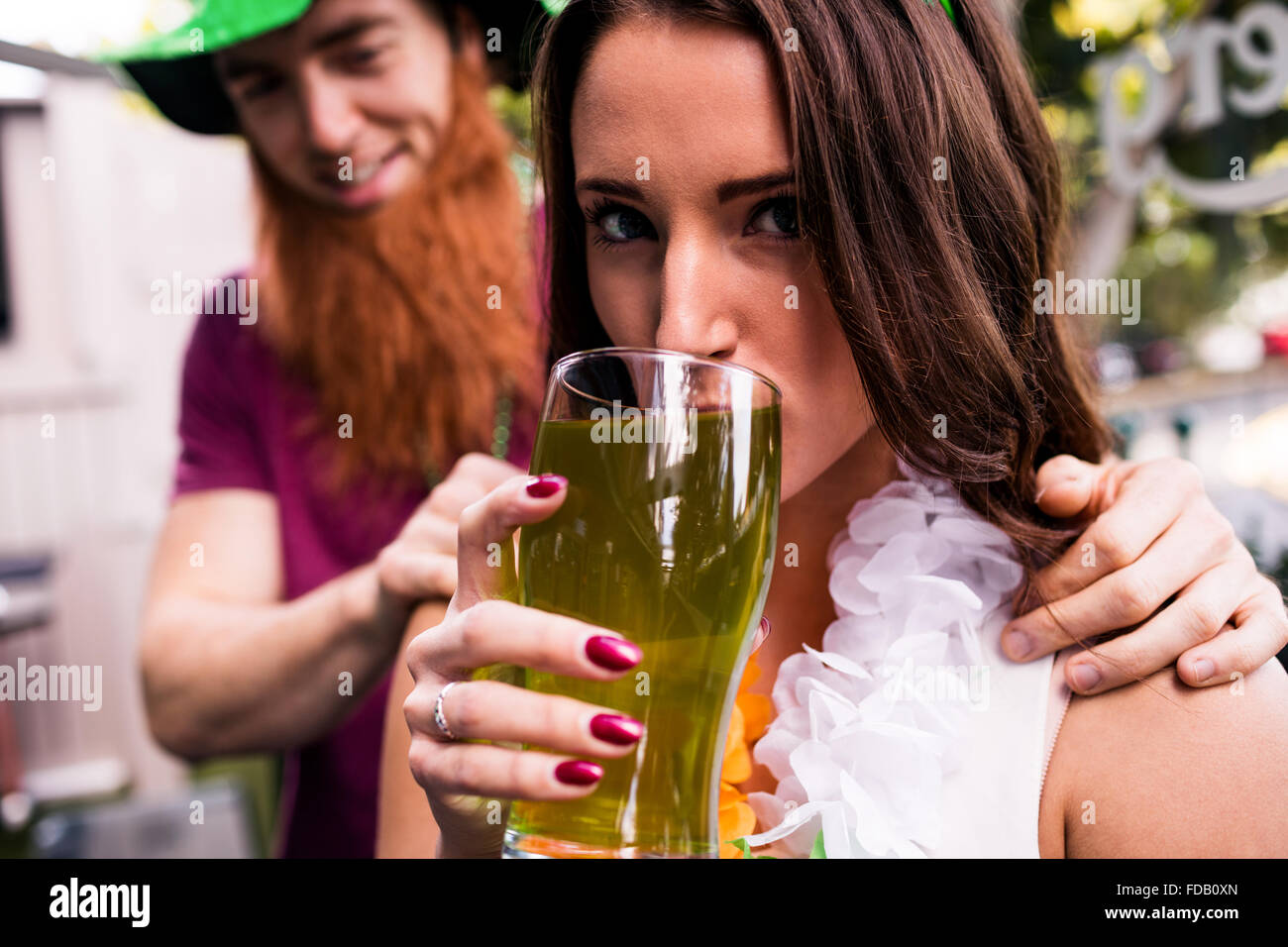 Verschleierte Frau hält ein grünes Bier Stockfoto