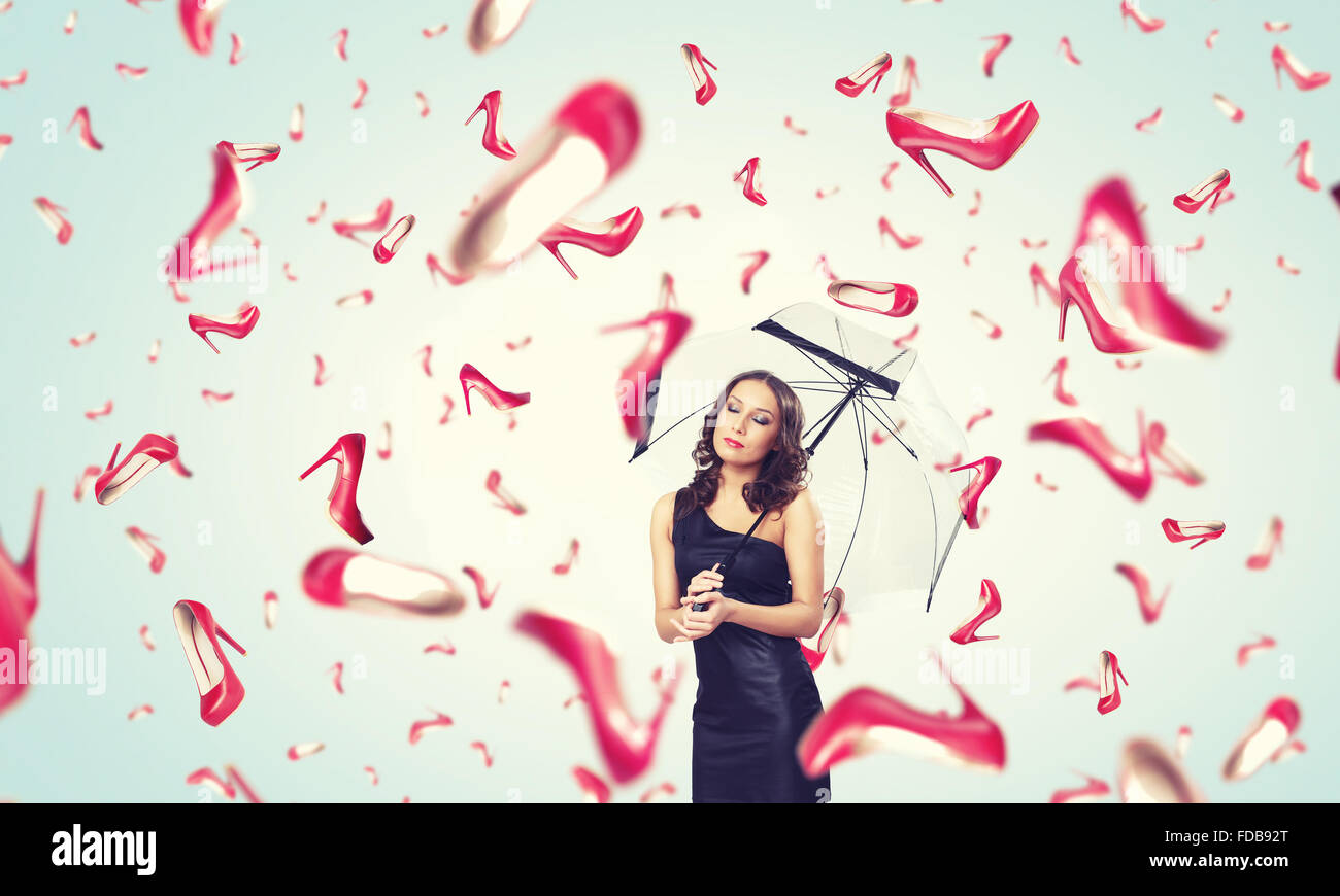 Schöne junge Frau mit Regenschirm und fallende Schuhe Stockfoto