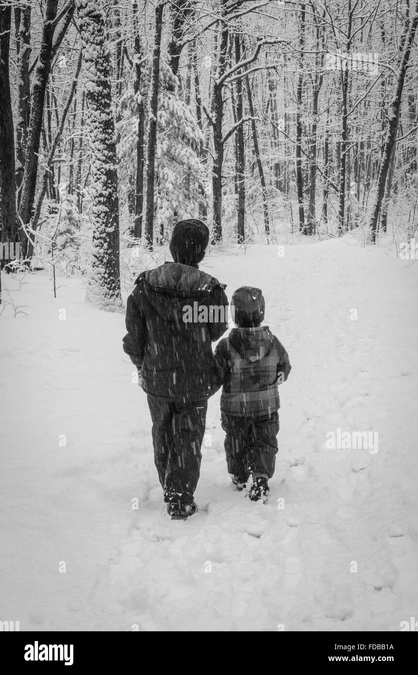 Zwei Brüder machen Sie einen Spaziergang hinunter eine Spur in einem Schneesturm. Stockfoto