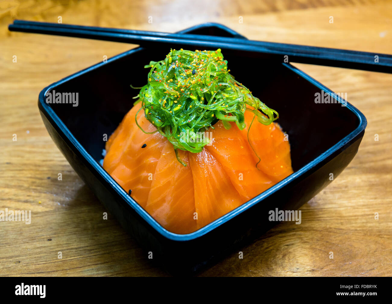 Tasse Lachs Sushi und grüne Algen an der Spitze Stockfoto