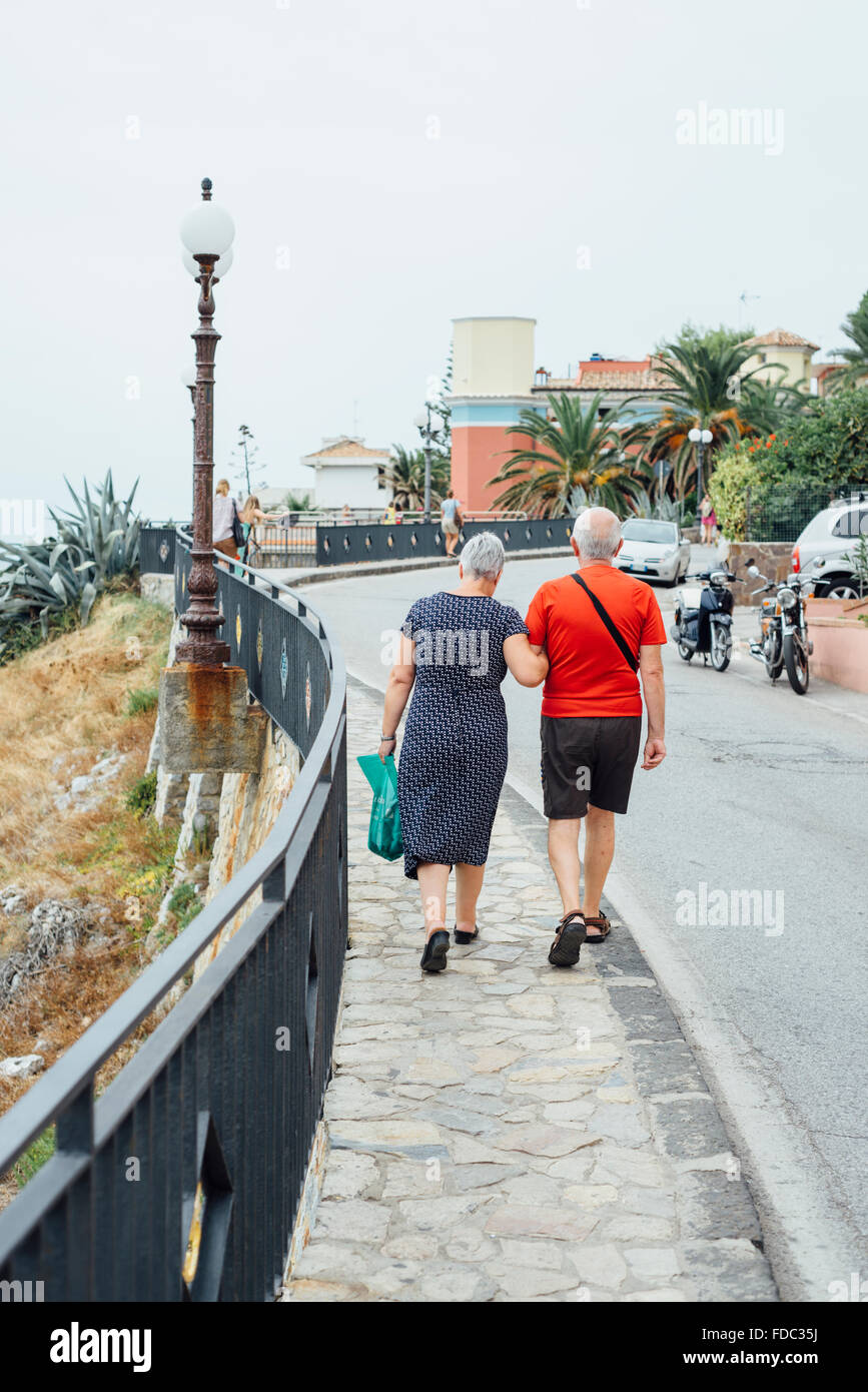 Blick auf Rückseite älteres paar zu Fuß süchtig auf einer Straße in einer südlichen italienischen Küstenstadt Marina di Camerota, Kampanien, Italien Stockfoto