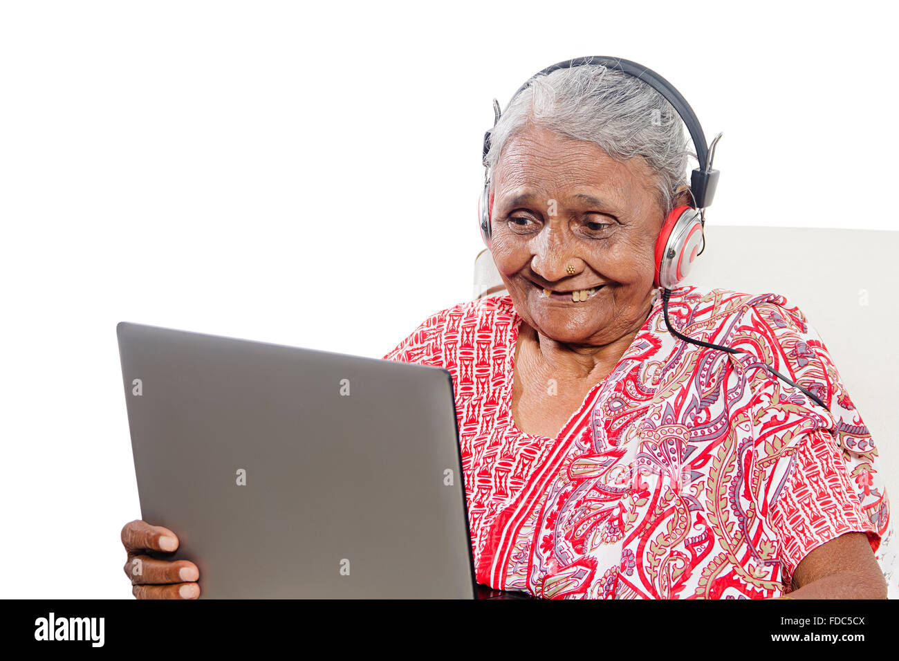 1 ältere Erwachsene Frau sitzen Sofa Laptop arbeiten und Kopfhörer Hören von Musik Stockfoto