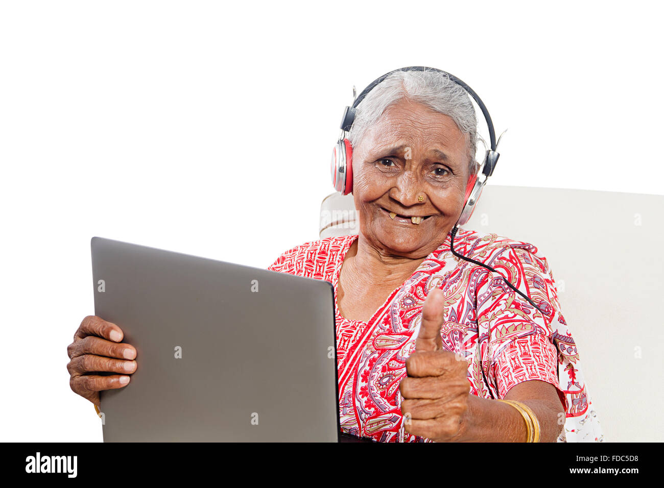 1 ältere Erwachsene Frau sitzen Sofa Laptop arbeiten und Daumen nach oben zeigt Stockfoto