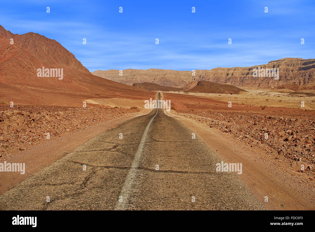 Asphaltierte Straße führt durch Arava-Wüste unter roten Berge im Nationalpark Timna, Israel. Stockfoto