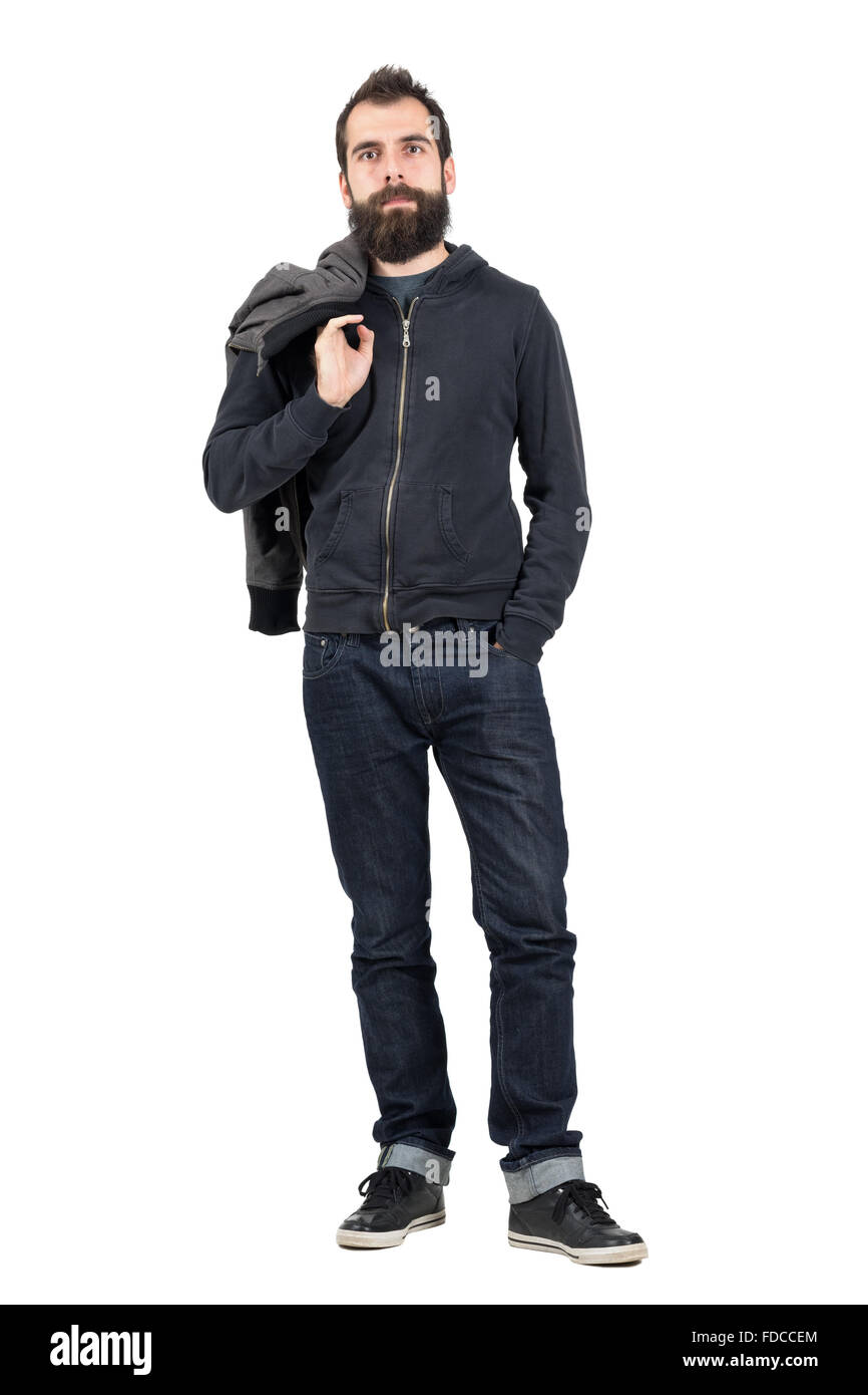Ernsthafte Hipster in Sweatshirt mit Kapuze Jacke über die Schulter, Blick in die Kamera zu tragen. Ganzkörper-Länge-Porträt isoliert Stockfoto