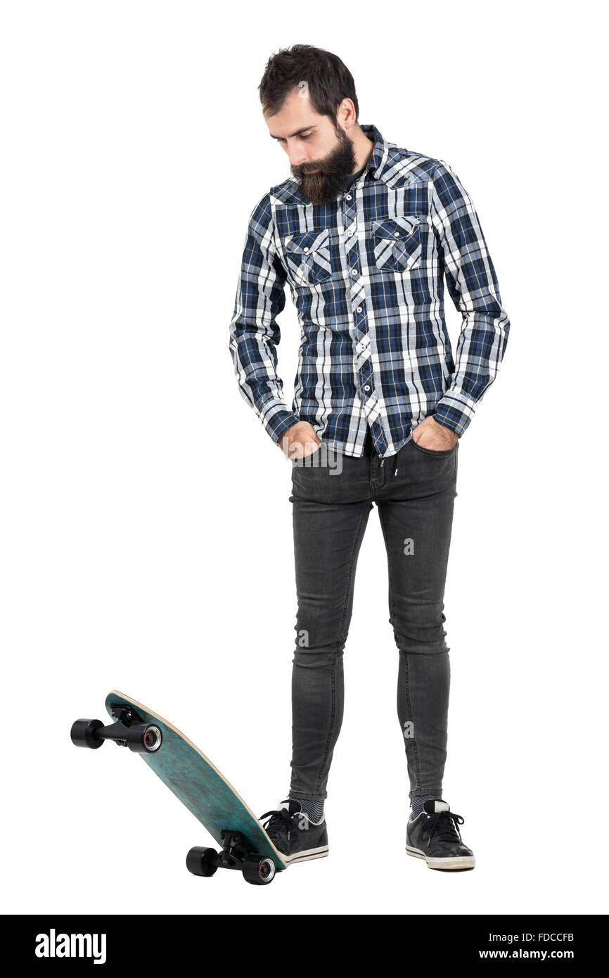 Bärtige Hipster auf Skate Longboard mit Händen in der Tasche nach unten stehen. Ganzkörper-Länge-Porträt über weißen isoliert Stockfoto