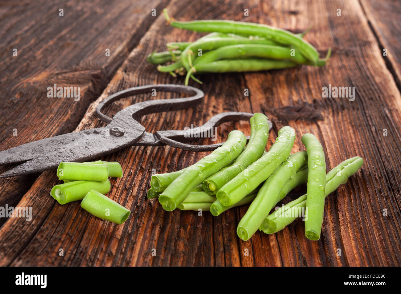 Rohe frische grüne Bohnen mit Wassertropfen auf braun strukturierte Holztisch. Frisches Gemüse essen. Stockfoto