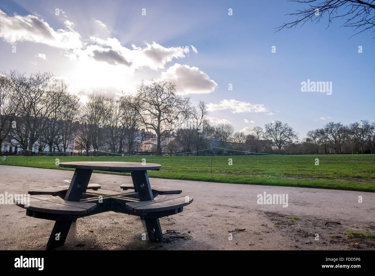 Parkbank gegen Sonne, Wolken und blauer Himmel Stockfoto
