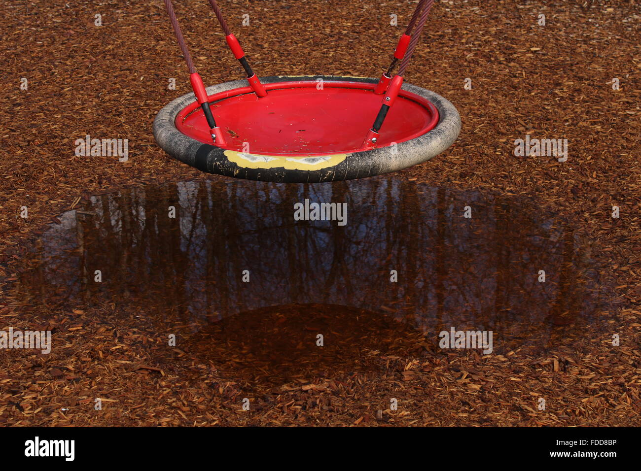 Spielplatz swing über Regen Pfütze reflektieren Bäume ausgesetzt. Stockfoto