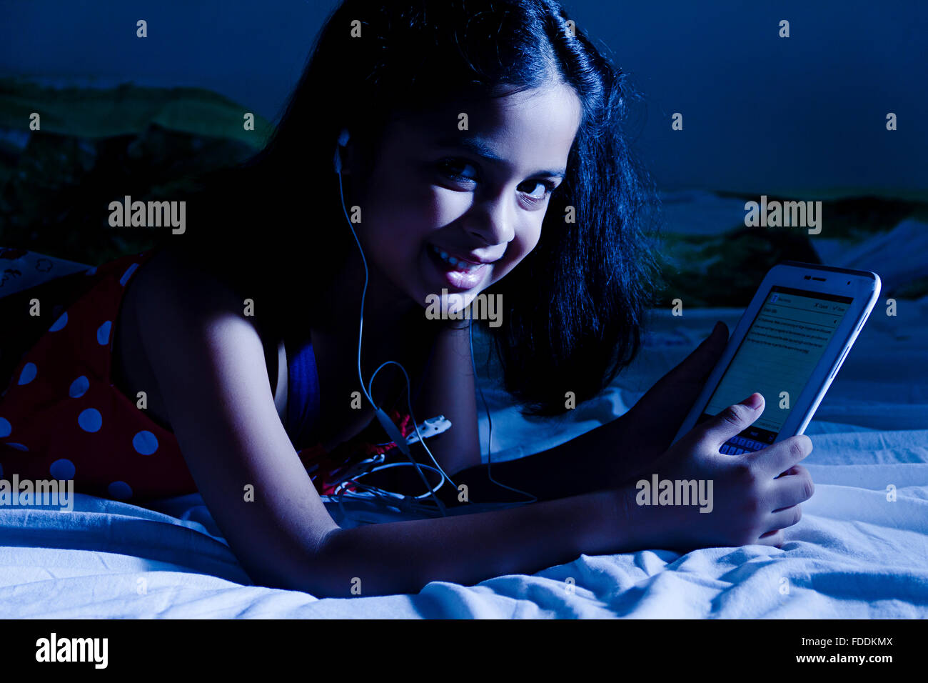 Ein Kind Mädchen Schlafzimmer Liegend Digital Tablet Hören Music Entertainment Stockfoto