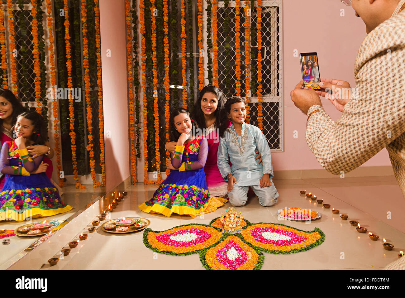 4 Personen Eltern und Kinder Diwali Festivals Home Rangoli Dekoration und Handy Klick auf Bild Stockfoto
