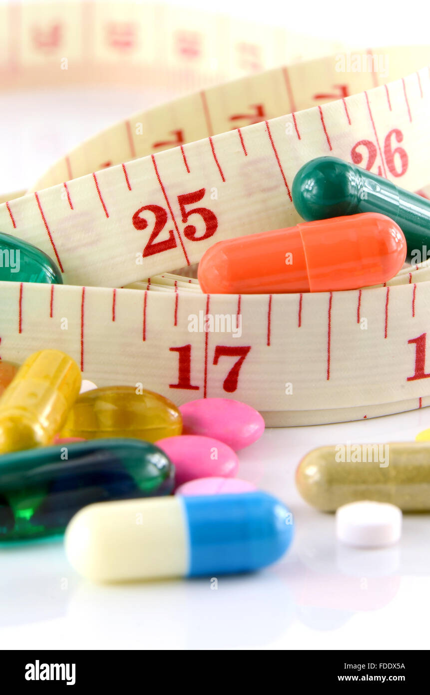 Medizin und Maßband auf weißem Hintergrund in Taille und Gewicht Steuerungskonzept. Stockfoto
