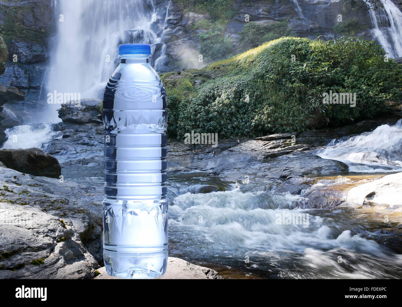 Flasche frisches Mineralwasser mit Wasserfällen im Hintergrund Stockfoto