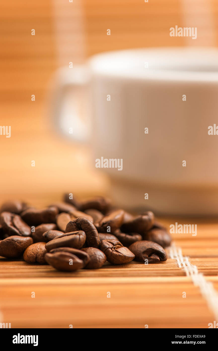 flache seitlicher Blick auf eine weiße Tasse auf Bambusmatte mit früheren Kaffeebohnen Stockfoto