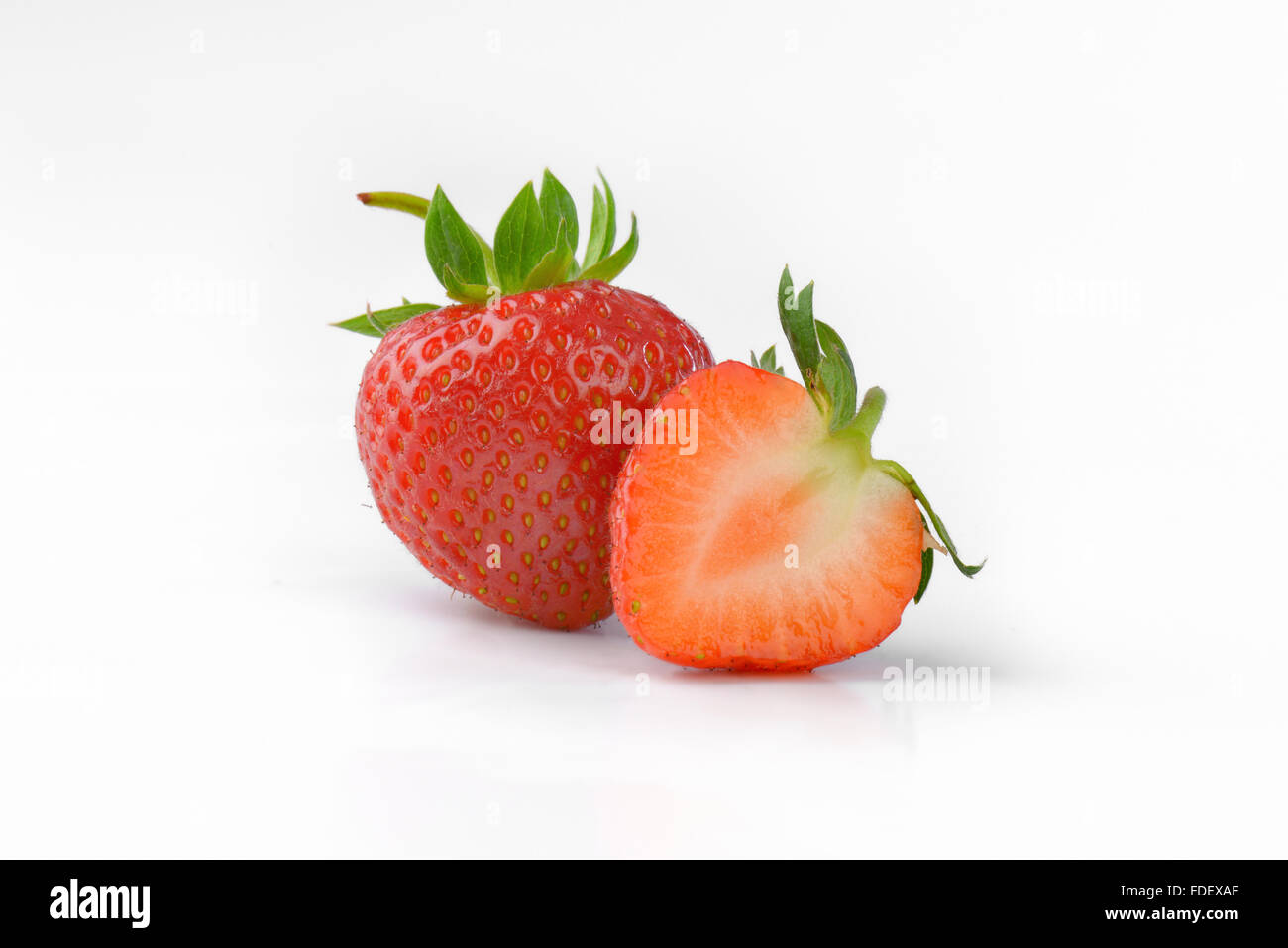 ein und eine halbe frische Erdbeeren auf weißem Hintergrund Stockfoto