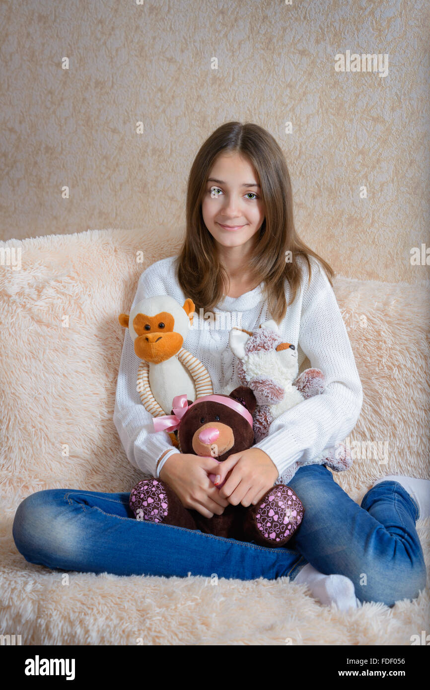 Mädchen mit Spielzeug sitzen auf der Couch mit einer Tagesdecke Fell Stockfoto