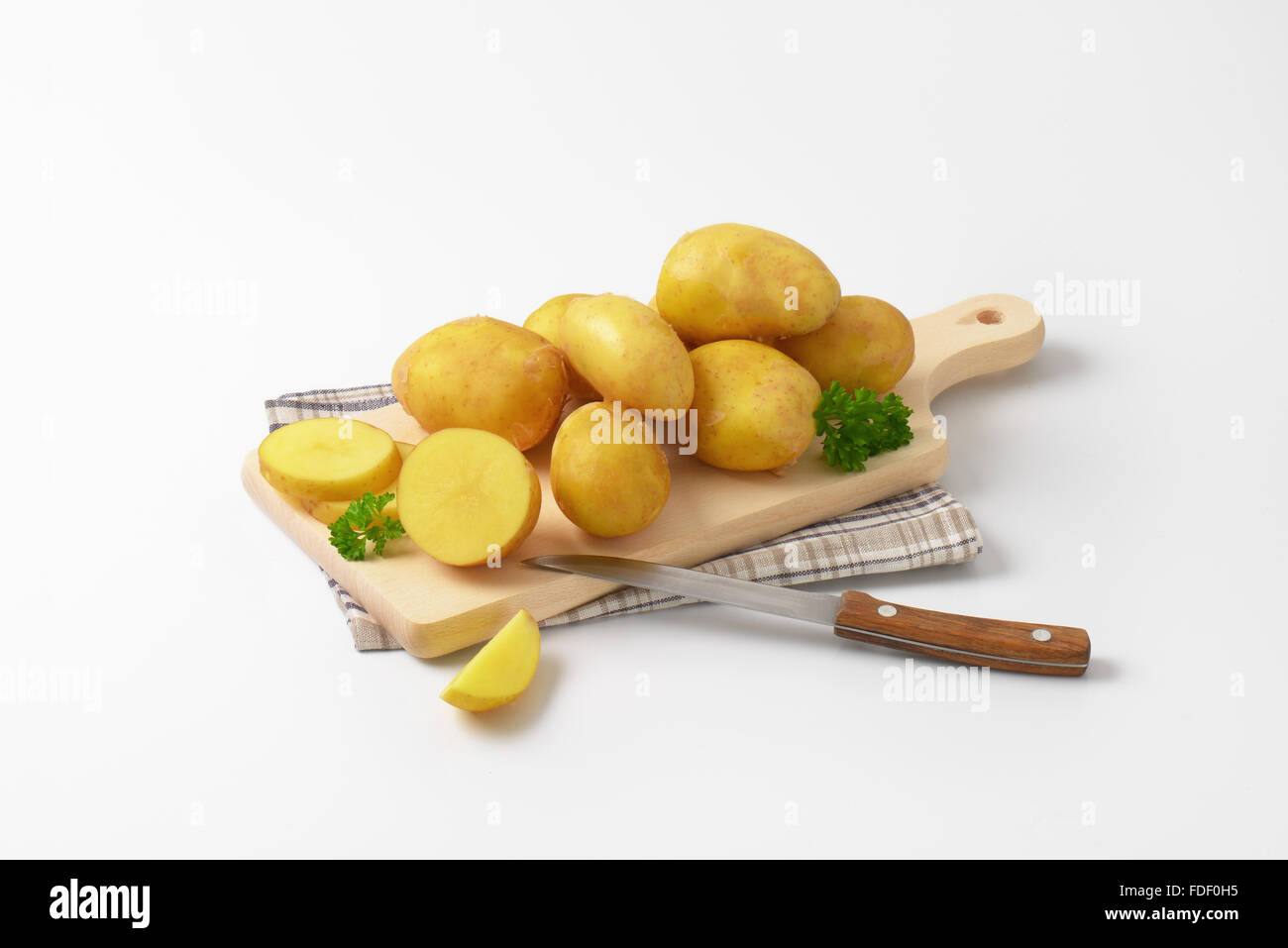 frische Babykartoffeln und Küchenmesser auf Holzbrett Stockfoto