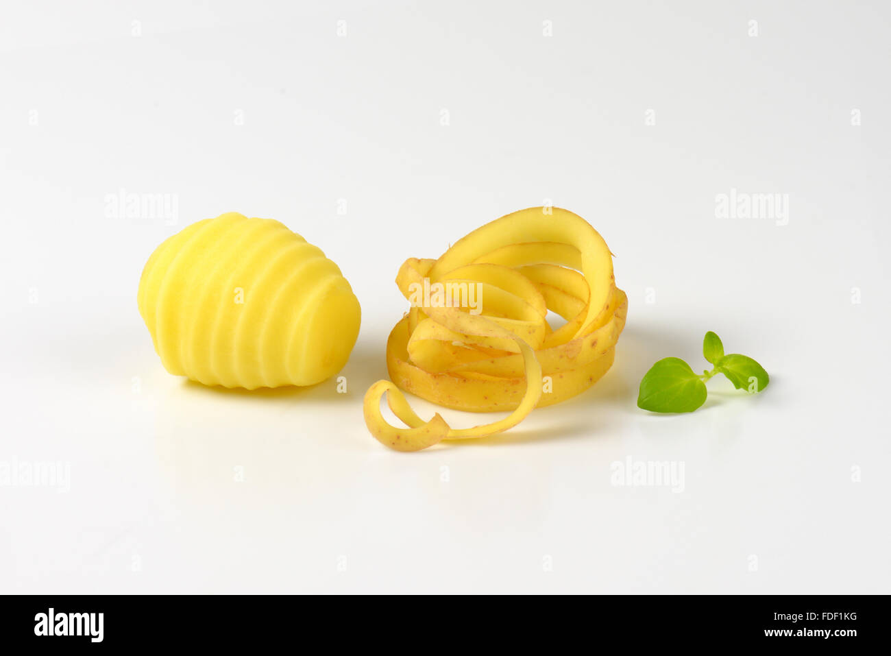 geschälte Kartoffeln und Peel Spirale auf weißem Hintergrund Stockfoto