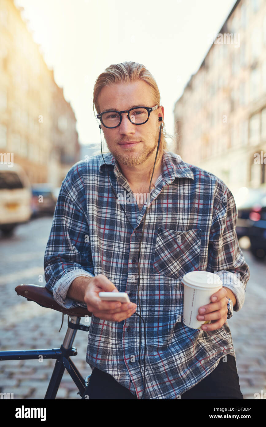 Porträt von cool junger Mann lebt in der Stadt hält eine Tasse Kaffee und sein Handy Stockfoto