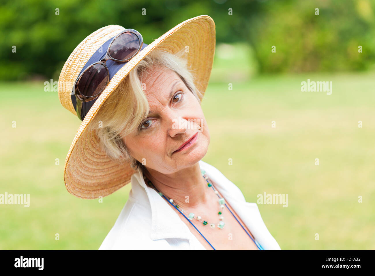 Senior alte Frau mit Hut lächelnd im freien Stockfoto