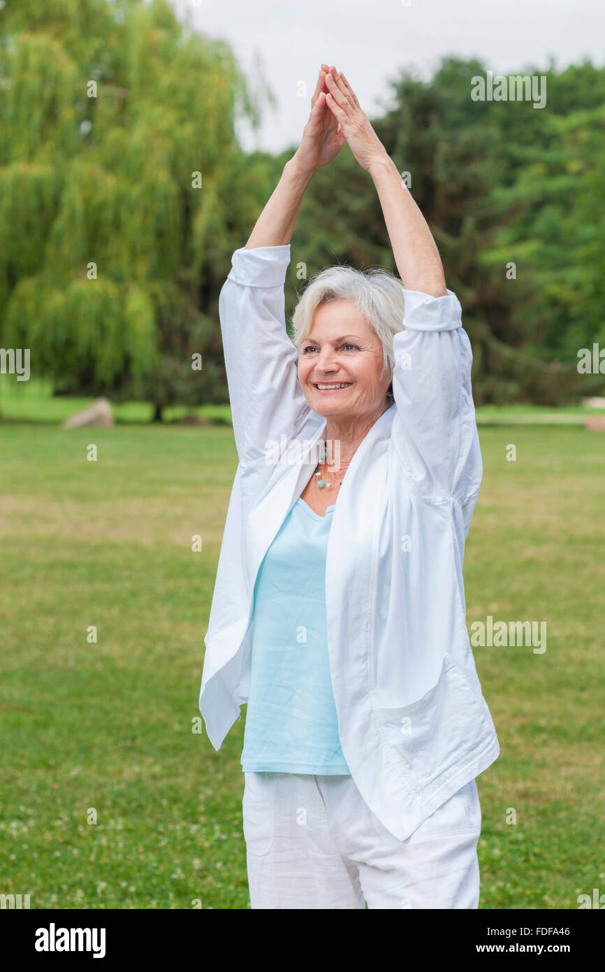 Senior gesunde alte Frau praktizieren Yoga und Tai Chi im freien Stockfoto