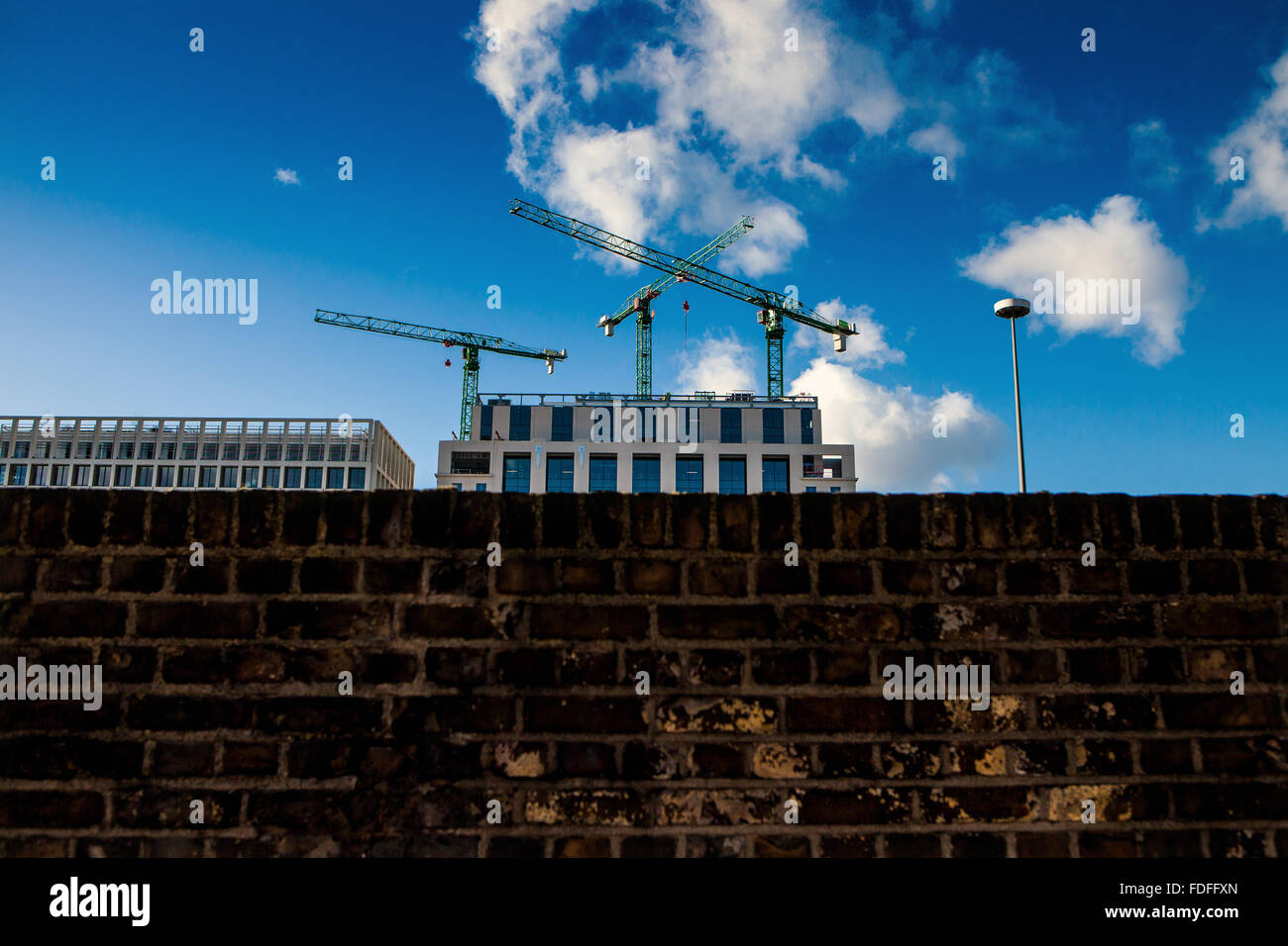 Baukräne sehen über alte Mauer Stockfoto