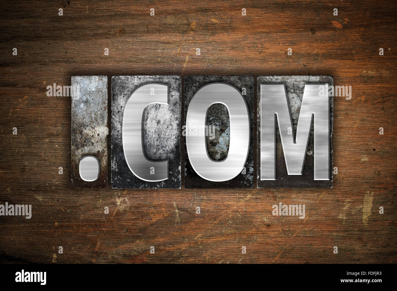 Das Wort "Dot Com" in Vintage Metall Buchdruck Typ auf einem alten hölzernen Hintergrund geschrieben. Stockfoto