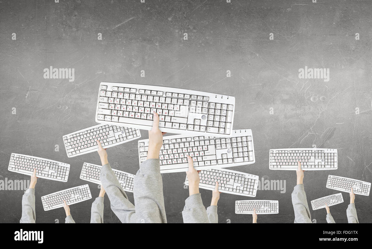 Gruppe von Geschäftsleuten, die Tastaturen in den erhobenen Händen halten Stockfoto