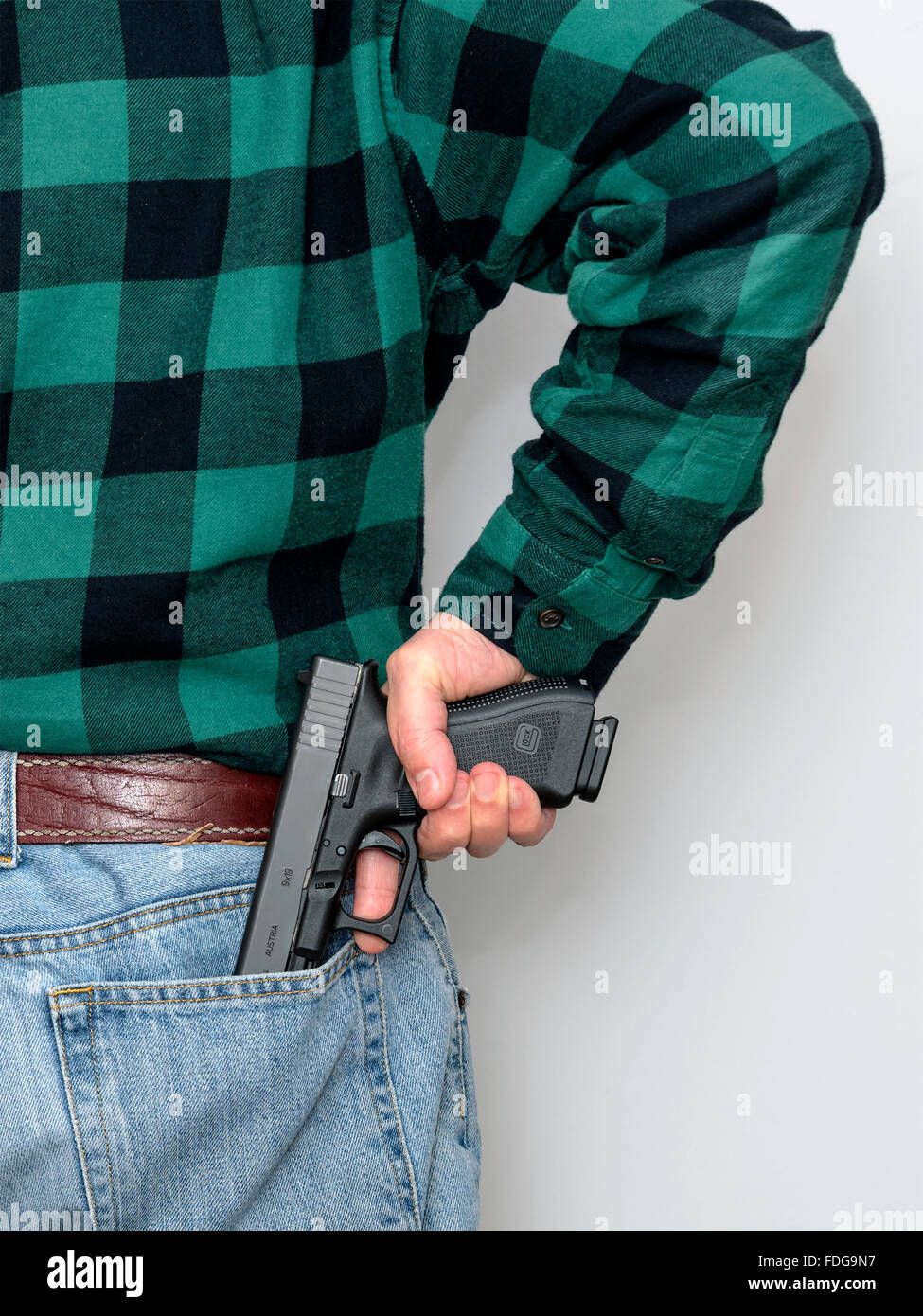 Der schnelle Mann nimmt eine Schusswaffe aus der Gesäßtasche der Hose Stockfoto