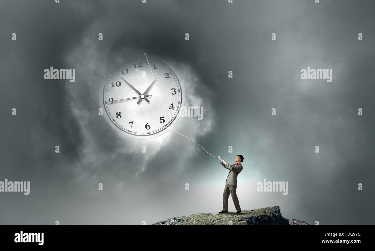 Junger Geschäftsmann versucht, turn back Time Uhr mit Seil ziehen Stockfoto
