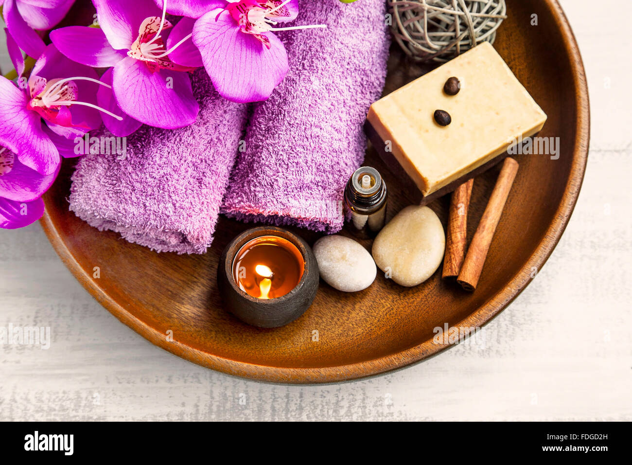 Wellness-Produkte in Holztablett mit Handtüchern, Duft Kerze, Orchidee, Badeöl Stockfoto
