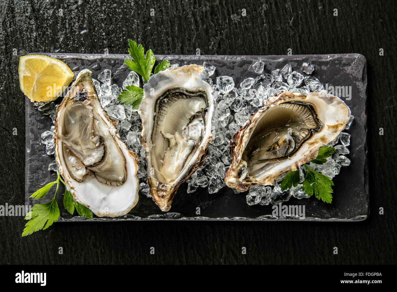 Austern auf Steinplatte serviert mit Eisgang Stockfoto