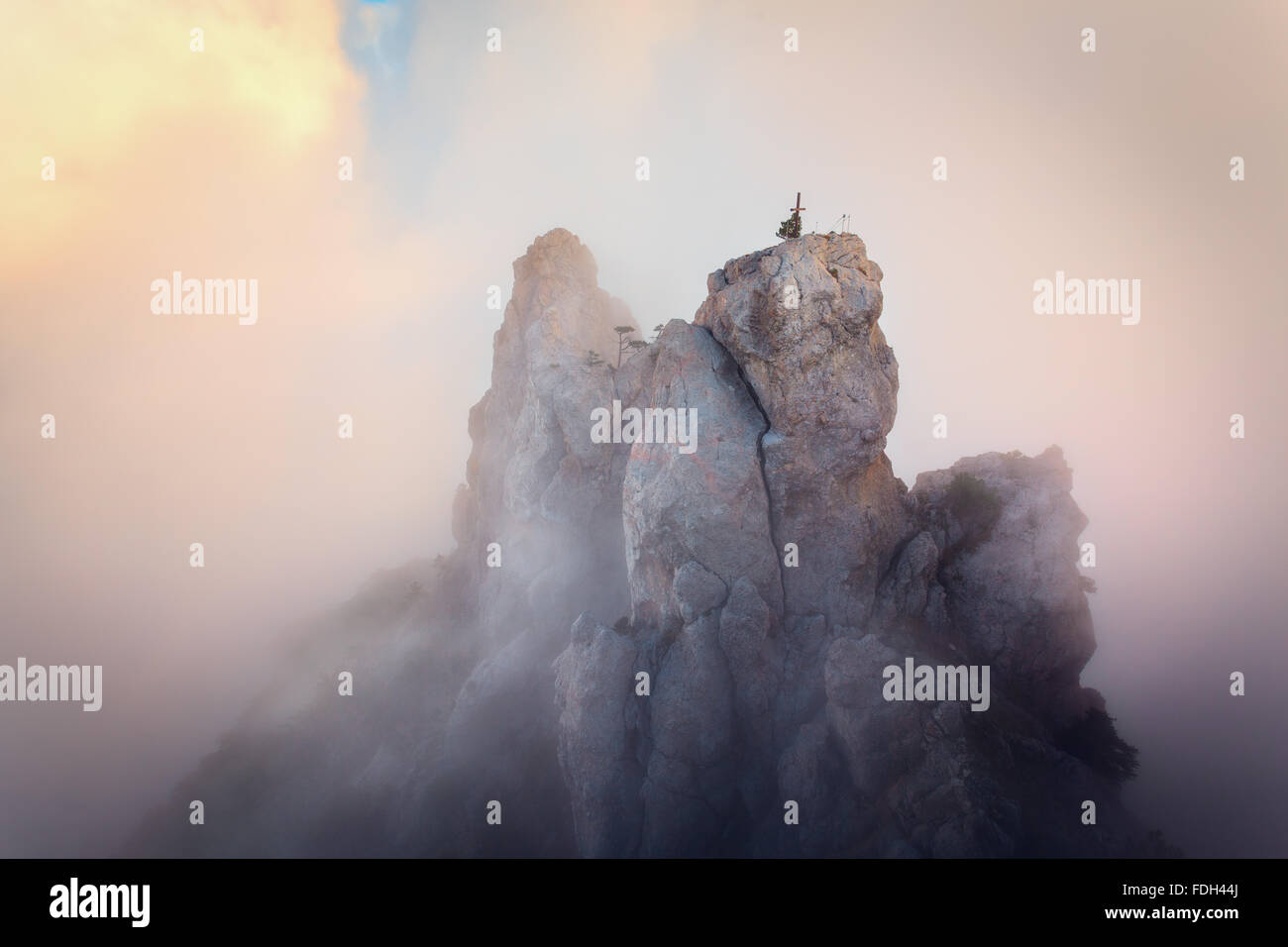 Oben auf den Bergen. Hohe Felsen im Nebel bei Sonnenuntergang. Bunte Natur Hintergrund Stockfoto