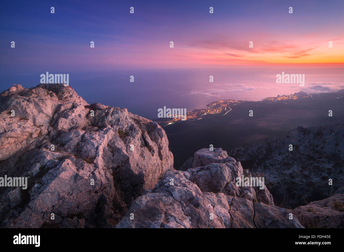 Schöne Nachtlandschaft auf dem Gipfel der Berge mit Meer, farbenprächtigen Sonnenuntergang und tief hängenden Wolken. Natur-Hintergrund Stockfoto