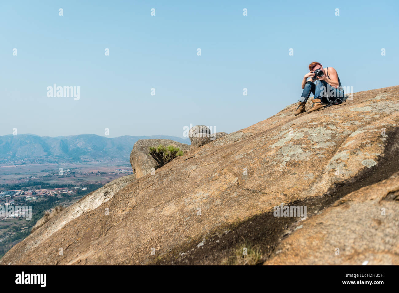 Mädchen mit dem Fotografieren auf einem großen Felsen in den Bergen von Mlilwane Wildlife Sanctuary in Swasiland, Afrika. Stockfoto