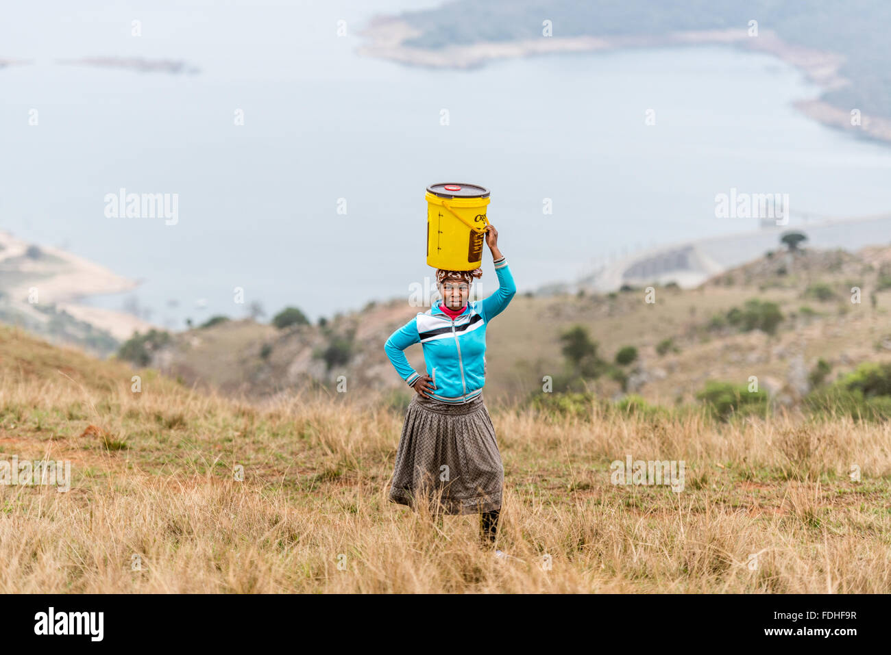 Frau mit einem Eimer auf dem Kopf in der Hhohho Region von Swasiland, Afrika. Stockfoto