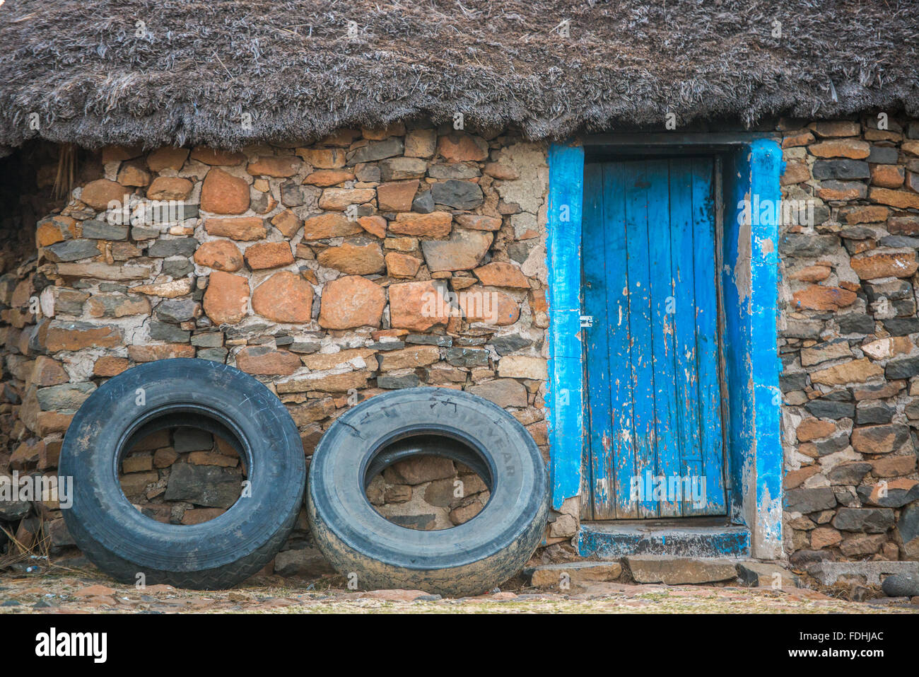 Dorf-Hütte-Tür mit 2 Reifen lehnt sich dagegen in Sani Pass, Lesotho, Afrika. Stockfoto