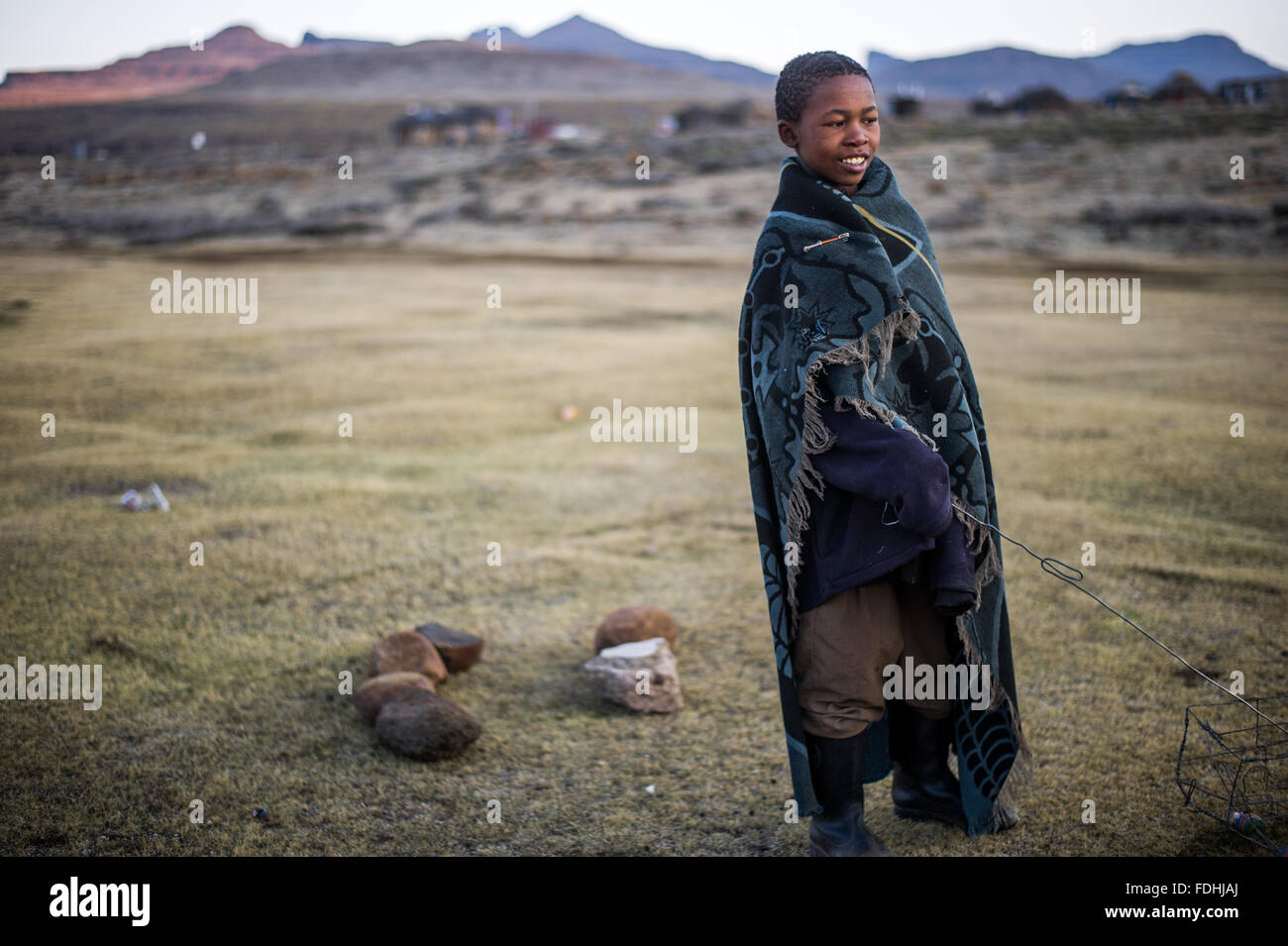 Porträt eines jungen Mannes in eine Decke gehüllt, mit Bergen im Hintergrund in Sani Pass, Lesotho, Afrika. Stockfoto