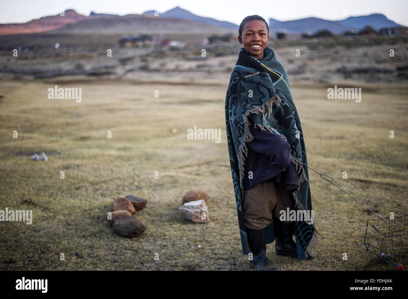 Porträt eines jungen Mannes in eine Decke gehüllt, mit Bergen im Hintergrund in Sani Pass, Lesotho, Afrika. Stockfoto