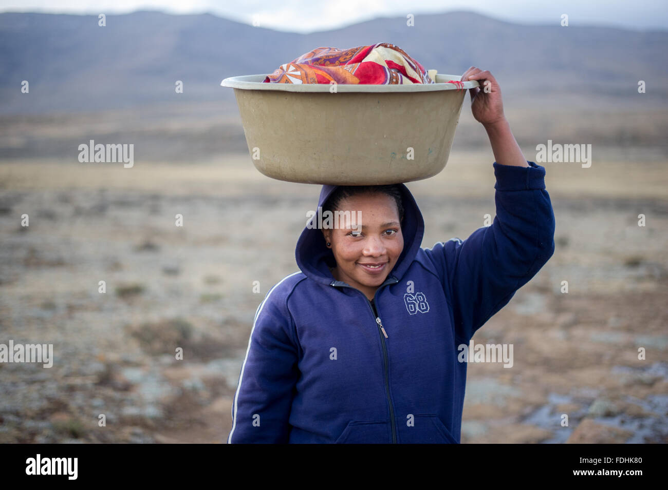 Porträt einer Frau einen Korb Wäsche auf dem Kopf in Sani Pass, Lesotho, Afrika. Stockfoto