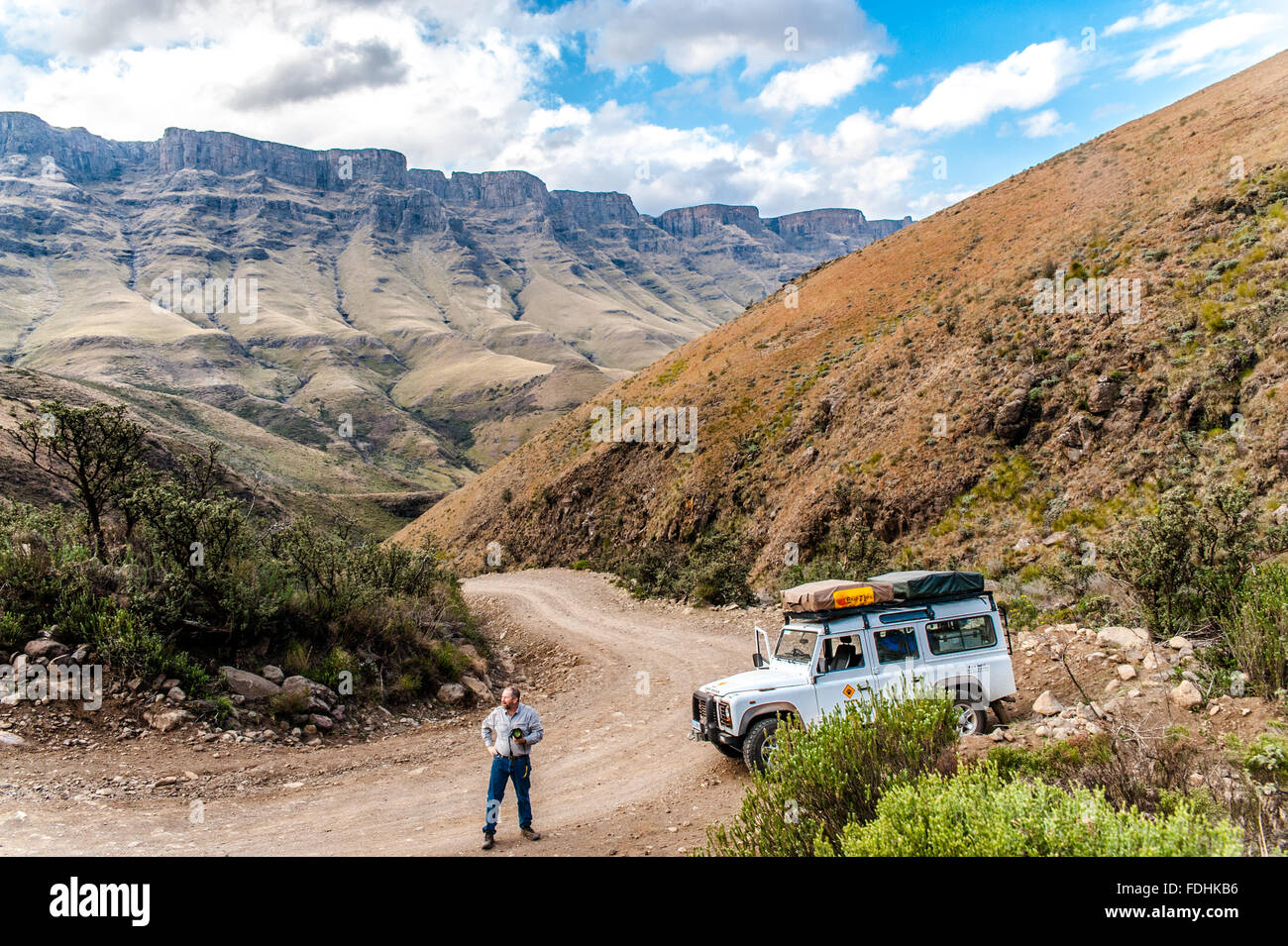 Land Rover Defender parkte auf einem Feldweg und ein Mann mit einer Kamera in Sanipass zwischen Südafrika und Lesotho Stockfoto