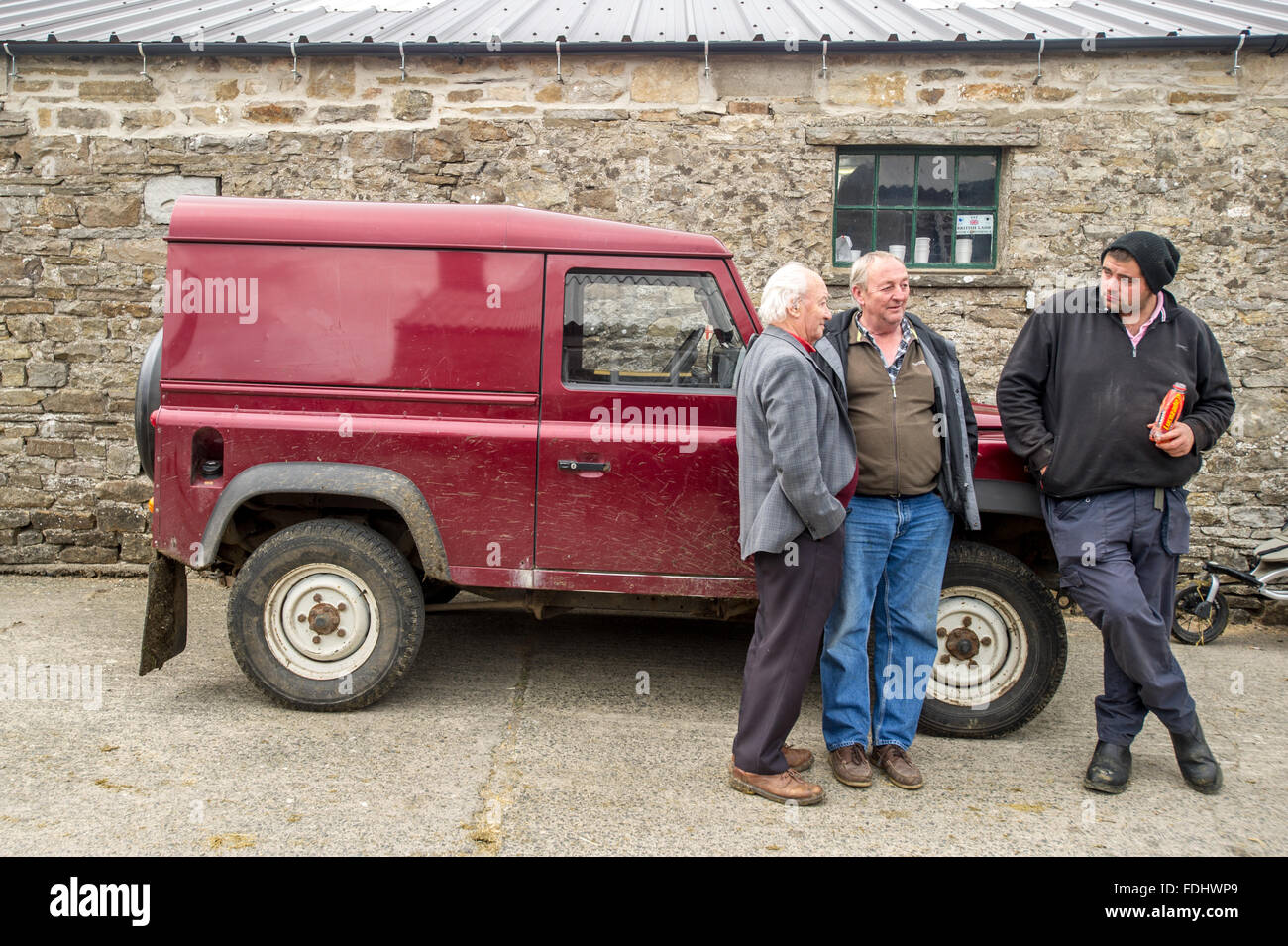 Drei Bauern stehen mit einem Landrover Defender bei Hawes Auktion Mart in Yorkshire, England, UK. Stockfoto