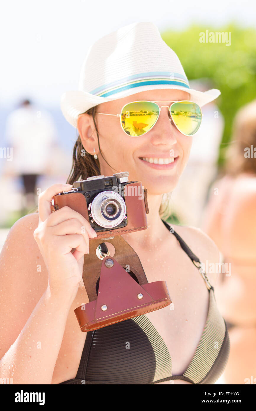 Glückliche junge Frau im schwarzen Bikini Spaß mit alten Foto-Kamera auf der Sommer-Urlaub am Meer. Stockfoto