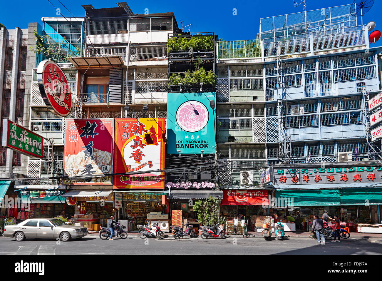 Sonnendurchflutete bunte Werbetafeln an Gebäuden an der Yaowarat Road in Chinatown, Bangkok, Thailand. Stockfoto