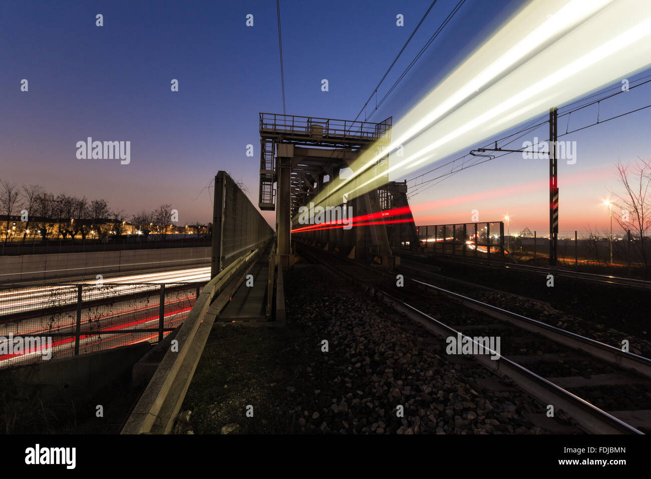 Langzeitbelichtung von einem vorbeifahrenden Zug auf der Brücke über die Autobahn Stockfoto