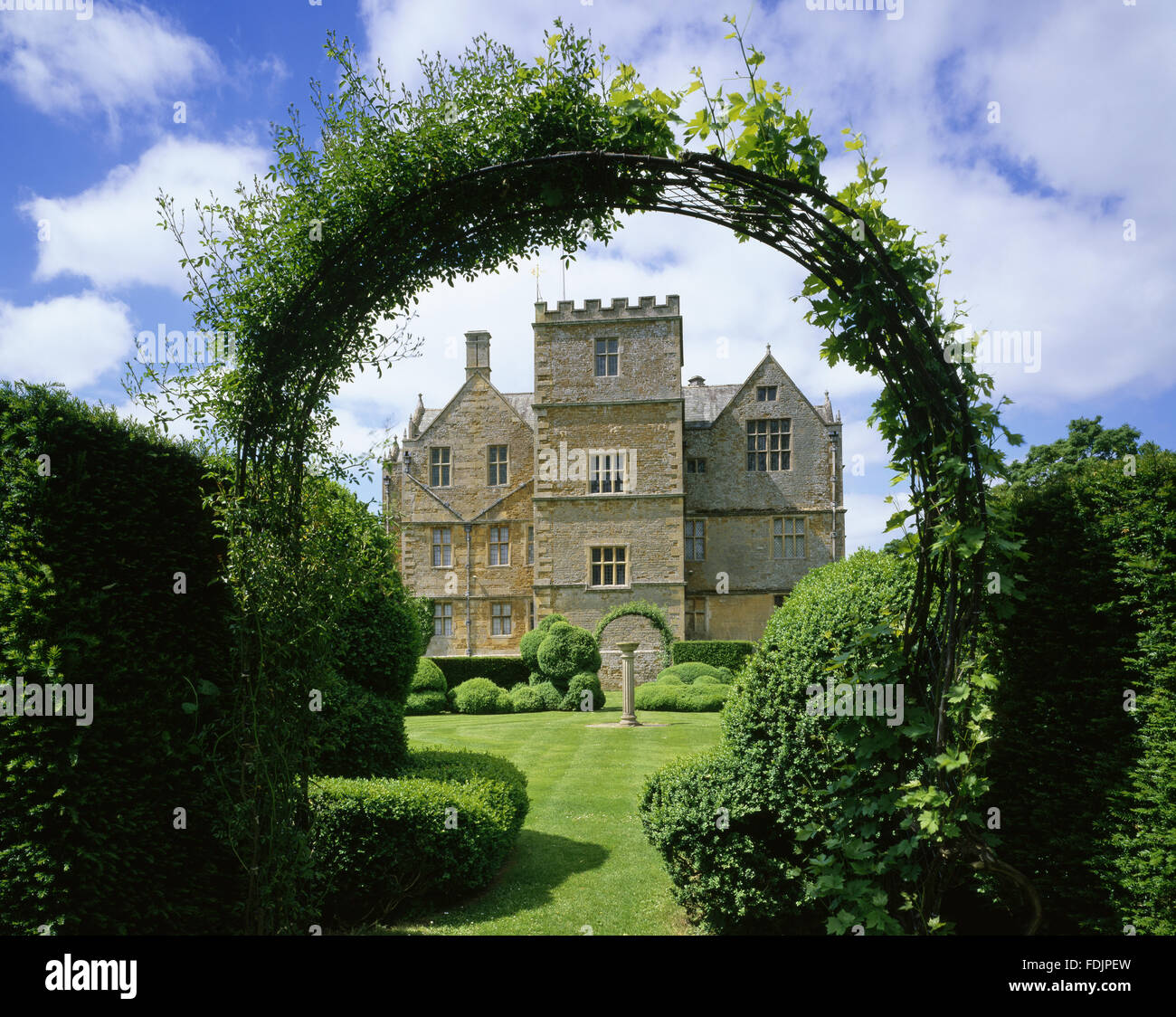 Die Ostfassade des Chastleton House, Oxfordshire, durch den Torbogen in die topiary Garten gesehen. Das Haus wurde im Jahre 1612 fertiggestellt, und der jakobinischen Gartengestaltung umfasst den Ring der ungewöhnlich geformte Hecke. Stockfoto