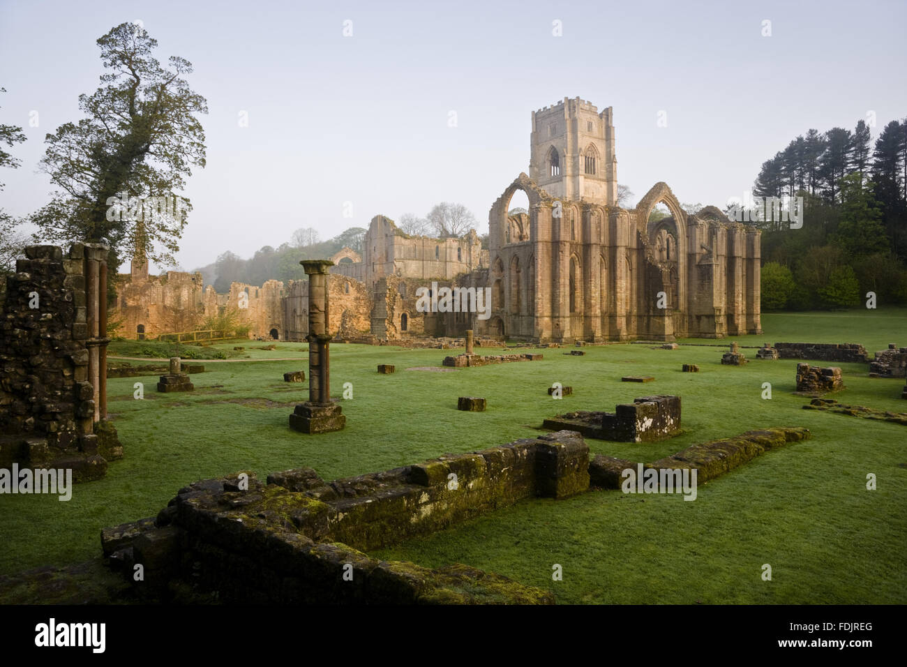 Ein Blick in Richtung Ostende der Abteikirche zeigt die große Osten Fensterbogen im Fountains Abbey, North Yorkshire. Reste von den Mönchen Krankenstation sind sichtbar im Vordergrund. Die Zisterzienser-Gemeinschaft der Mönche wurde hier 1132 gegründet aber war Beiträge Stockfoto