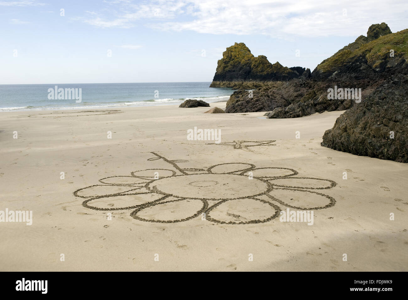 Eine riesige Blume zeichnen am Sandstrand bei Kynance Cove, Cornwall. Stockfoto